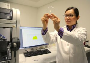 Woman in labcoat studying a 3D-printed ear.