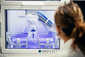 Kvinna i vit rock använder en 3D-printer i ett labb