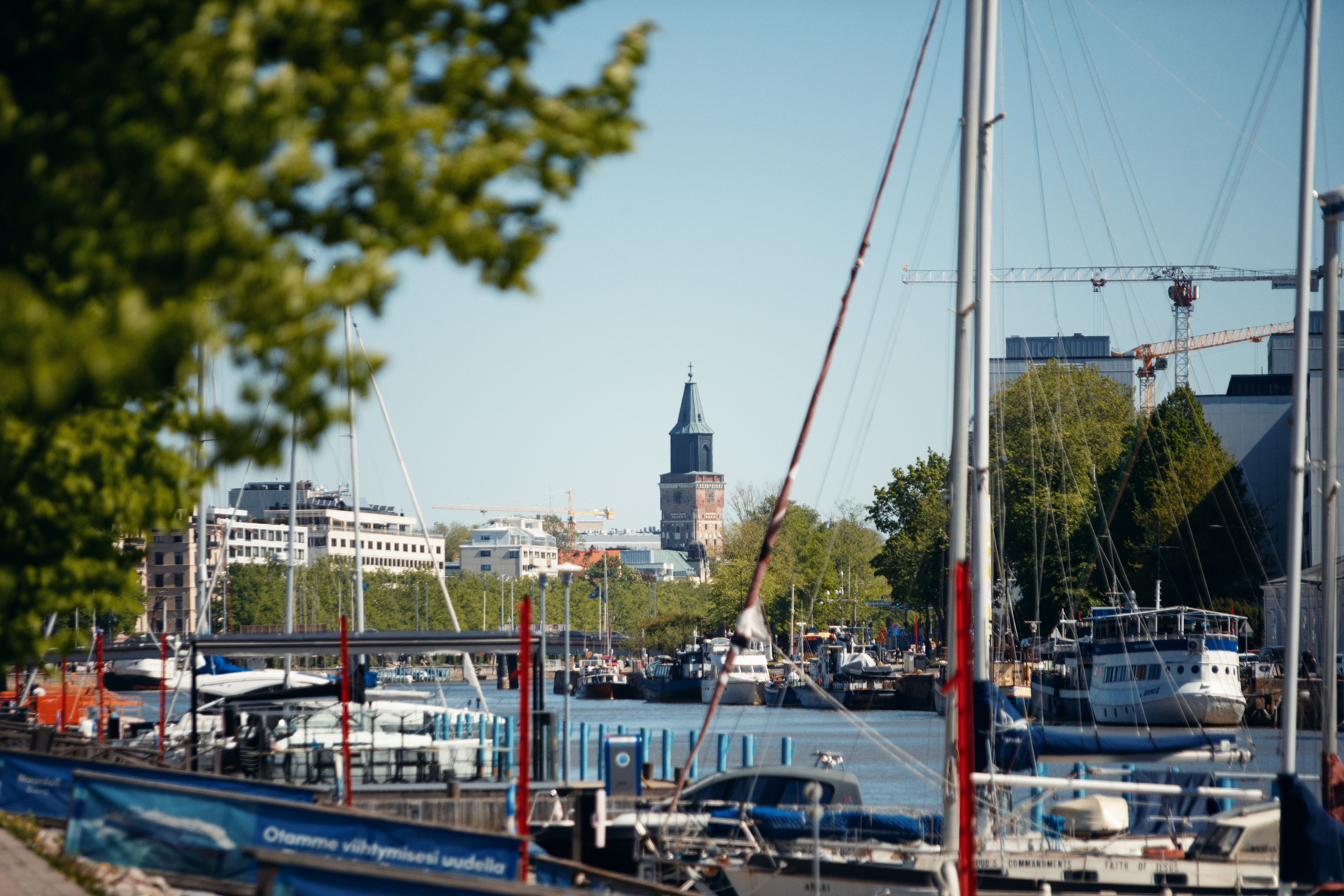 Båtar längs Aura å, höghus och kyrkan i bakgrunden