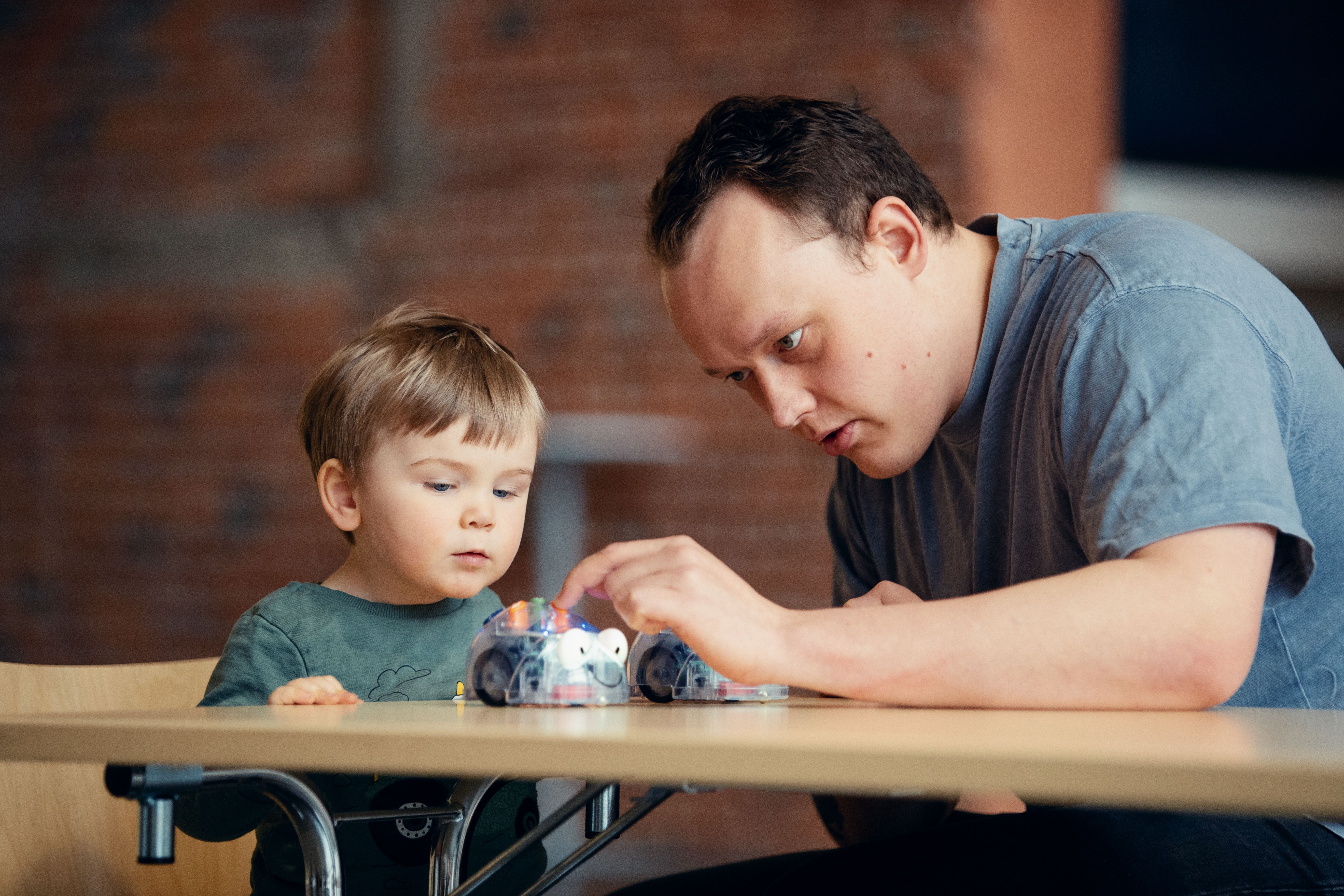 En man och en liten pojke leker med en leksak på ett bord