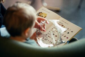 Närbild av en liten pojke och en kvinna som läser en bok tillsammans. Bilden är tagen bakifrån