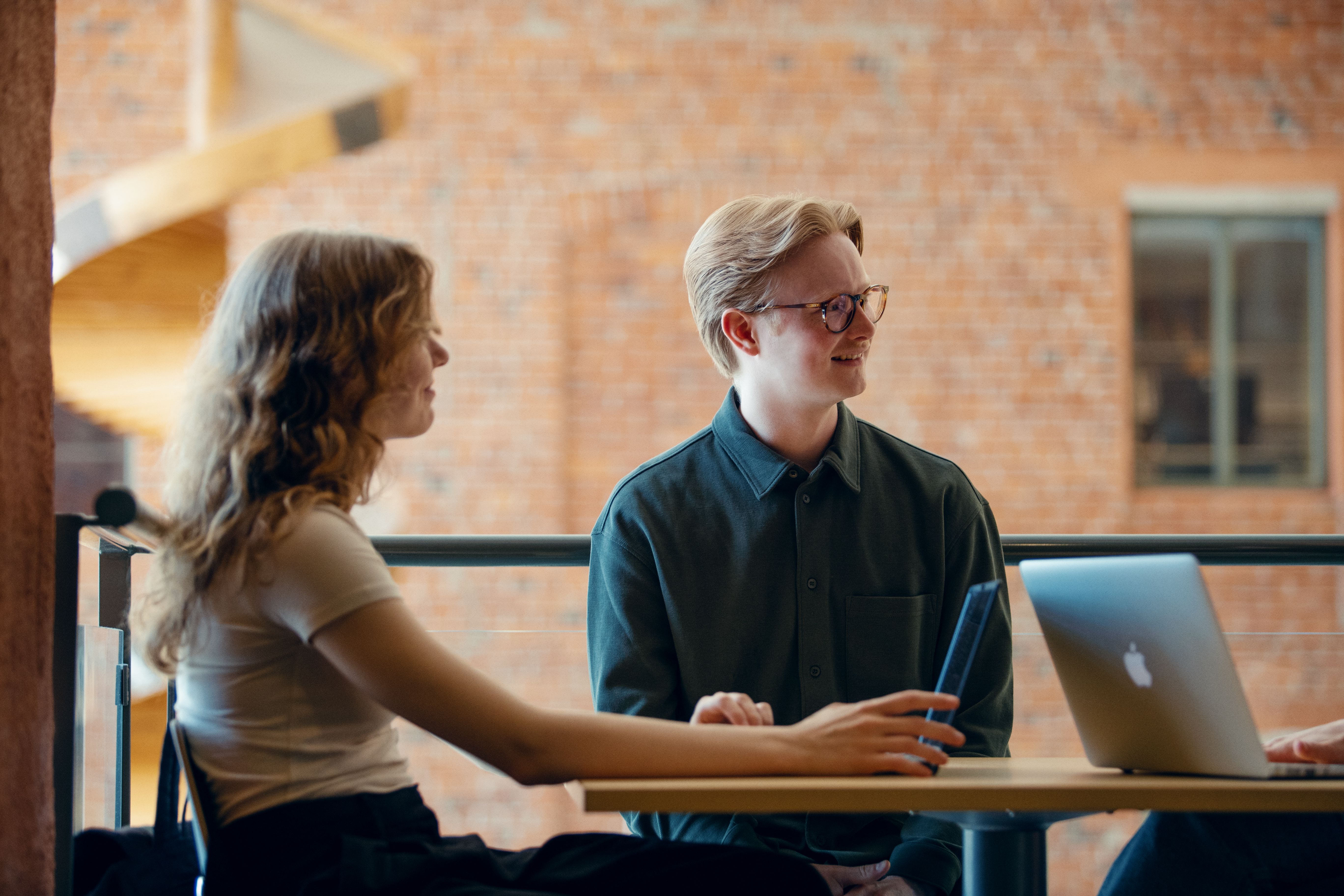 Två studerande sitter vid ett bord, de tittar både åt höger