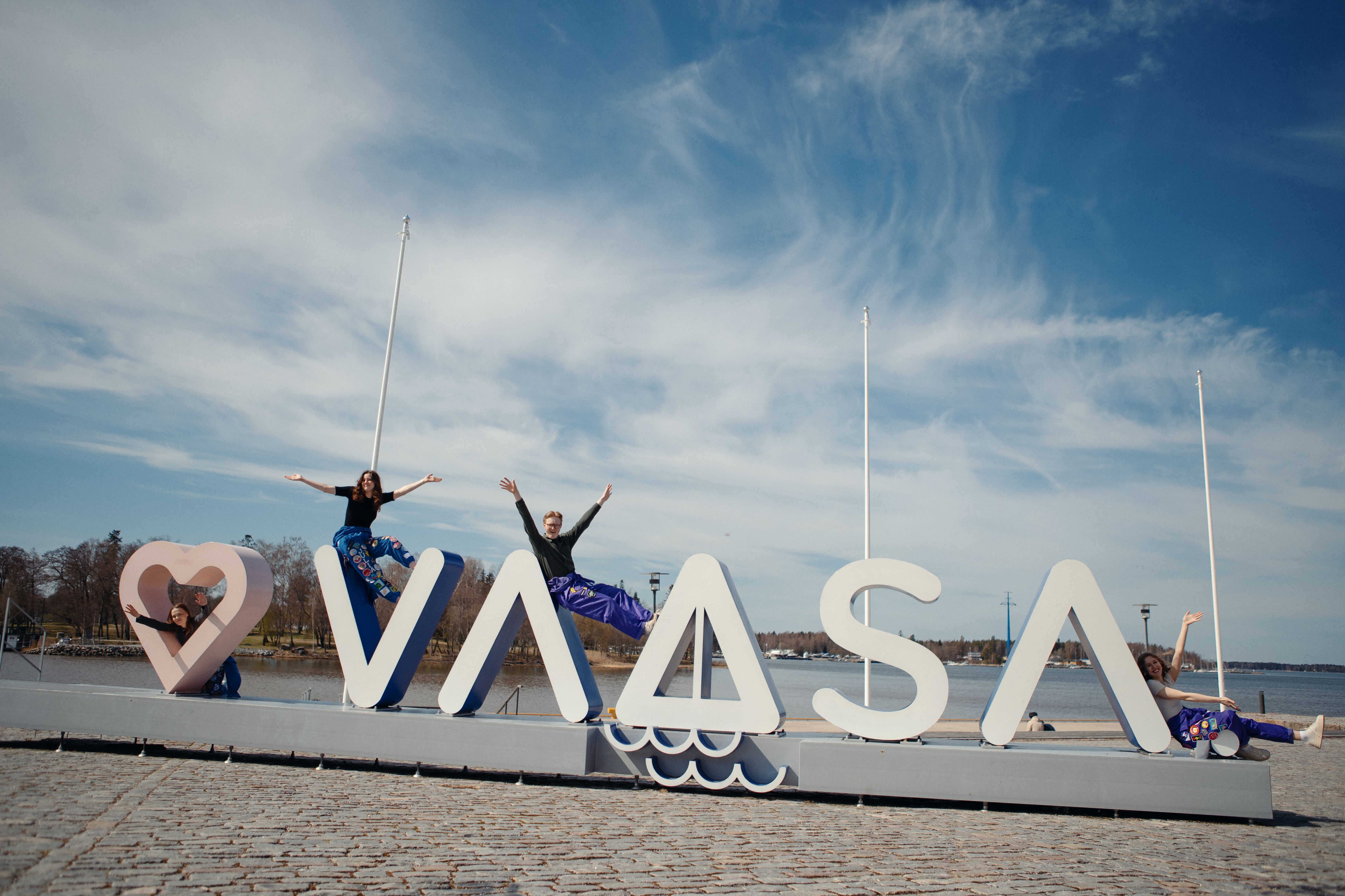 Studerande i lila halare vid Love Vaasa-skylten