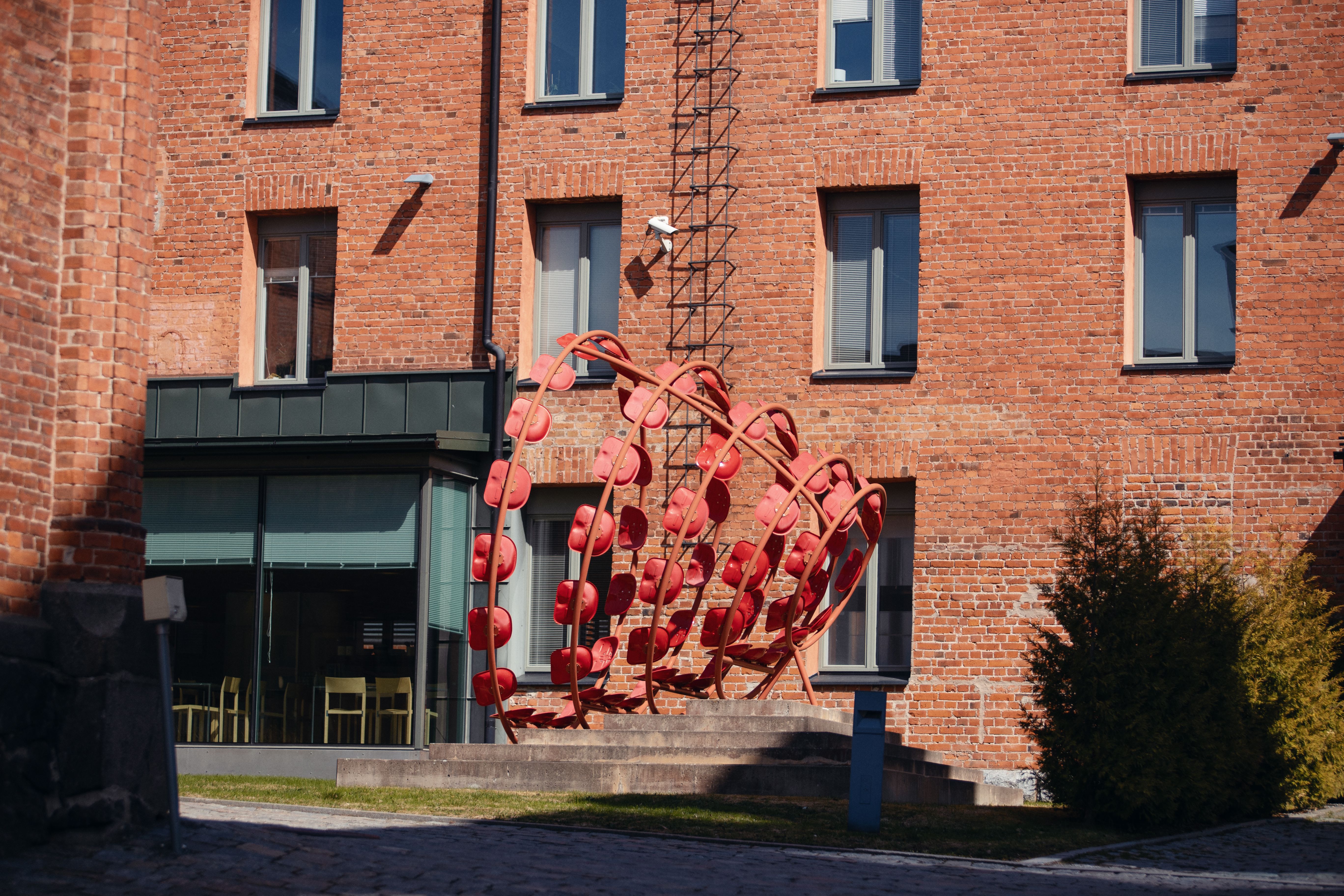 Innergård av en röd tegelbyggnad, med buskar och en gräsmatta