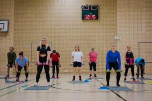 Personer som motionerar i gymnastiksal.