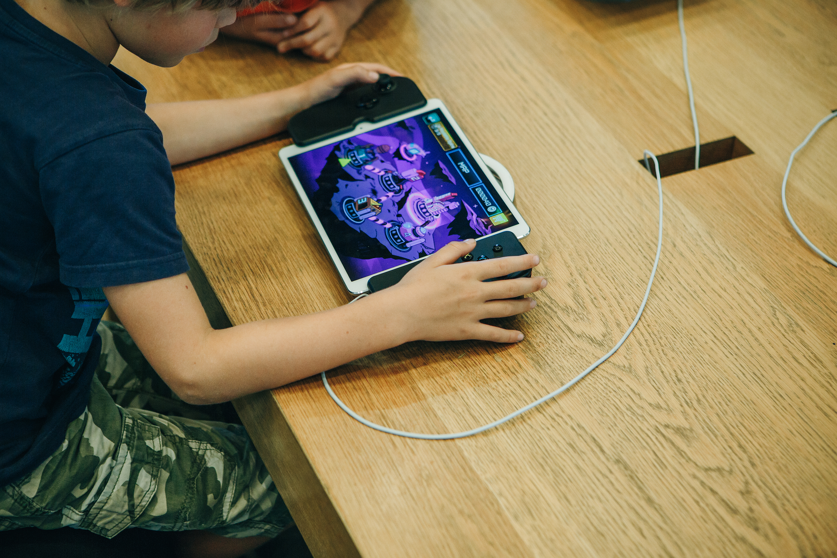 Ung pojke med IPad sitter vid ett bord och spelar ett spel.