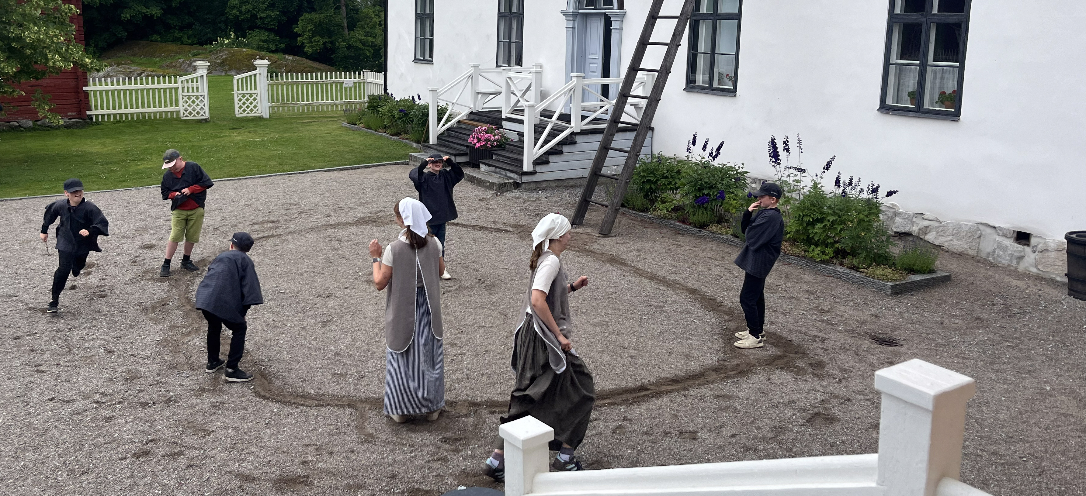 Barn utklädda i tidsenliga gamla kläder leker på en skolgård.