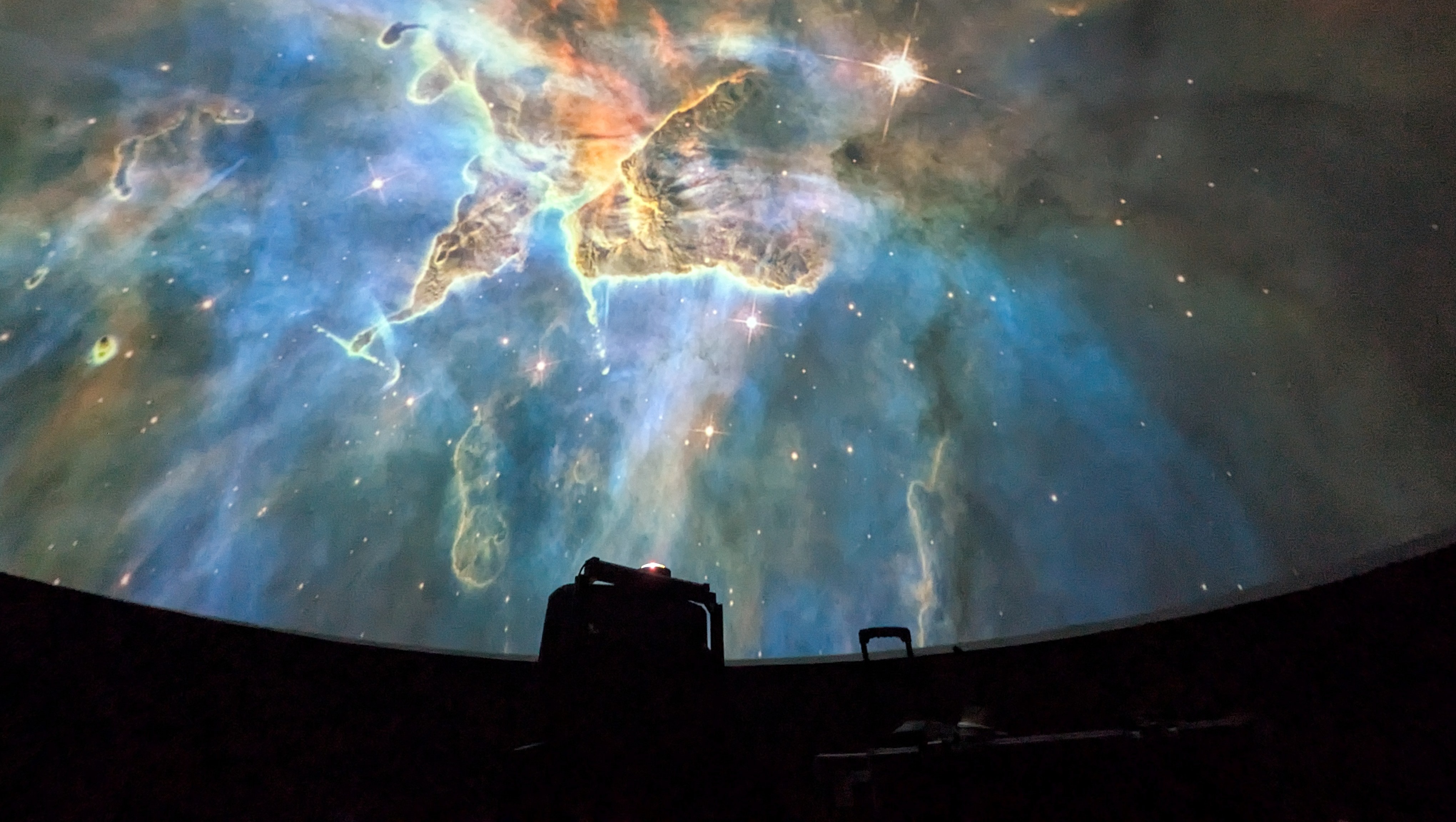 En projektor projicerar en bild av en nebulosa inne i ett planetarium.