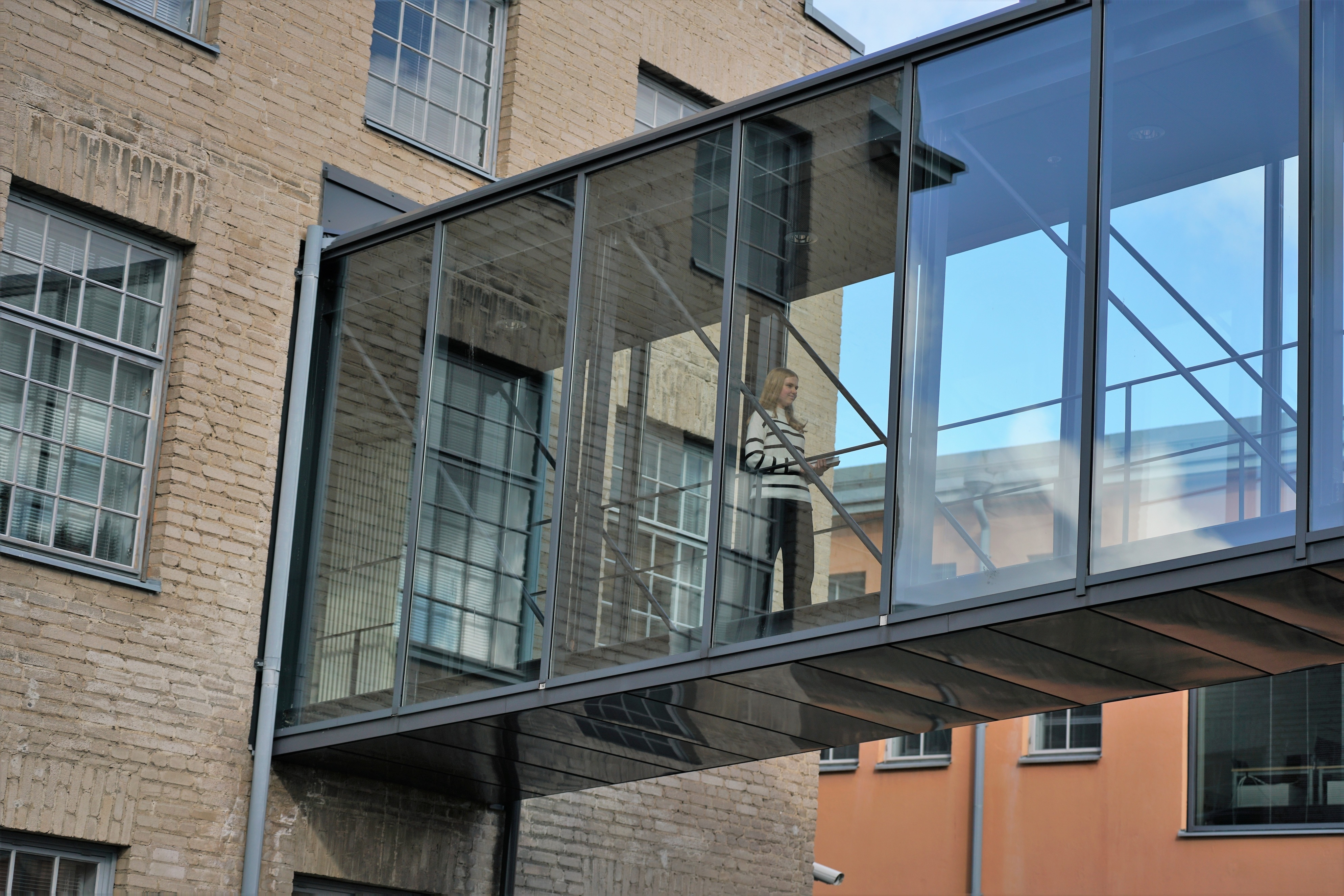 Bild på en studerande i glaskorridoren i Arken mellan B- och G-byggnaderna.