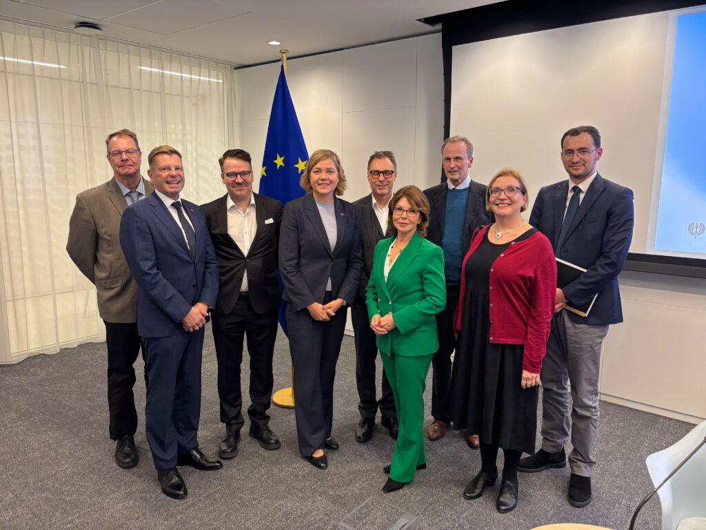 Group picture of people mentioned in the article. The EU flag is behind them.