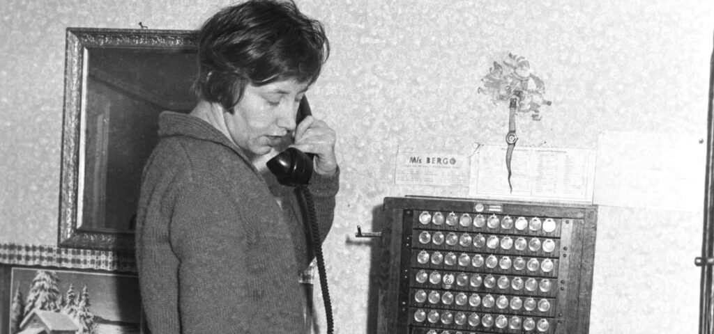 Svart-vit bild på en kvinna som svarar i telefoncentralen. 