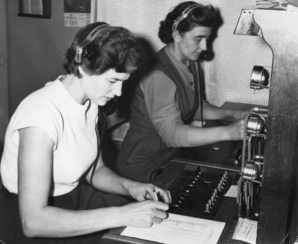 En svart-vit bild på två kvinnor som sitter vid centralbordet.