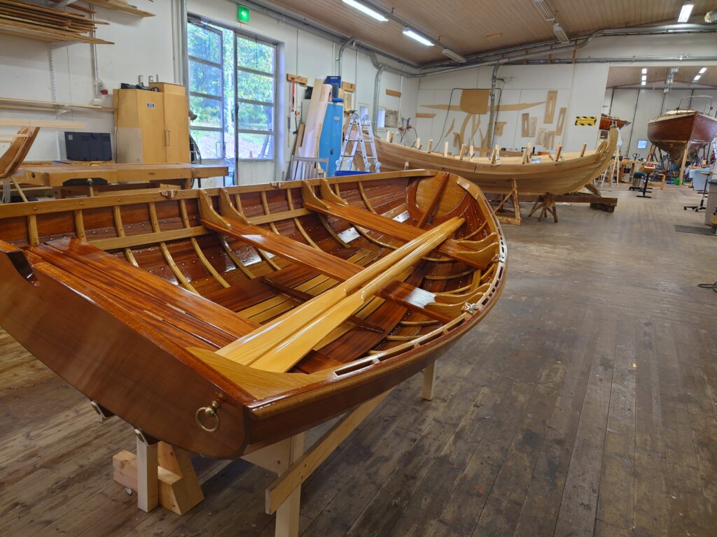 En vacker, lackad roddbåt i trä i en hall.