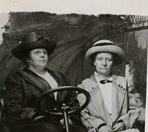 foto från 1919 med två damer i en fotostudio föreställande bilkörning